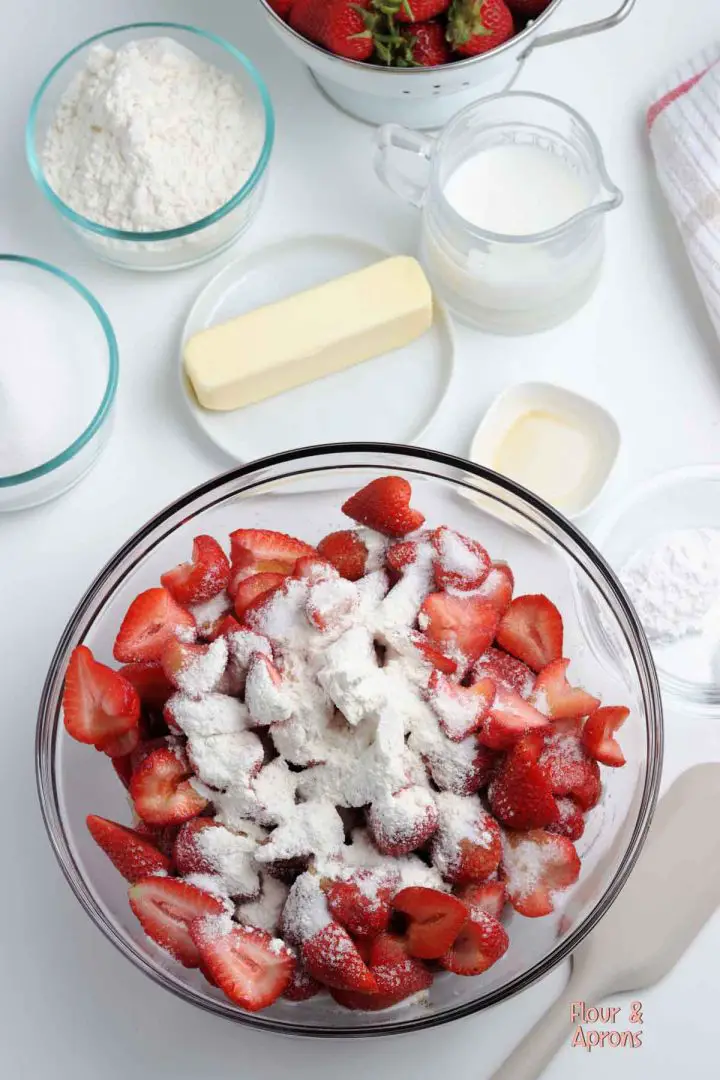 Strawberries in bowl with sugar and flour on top.