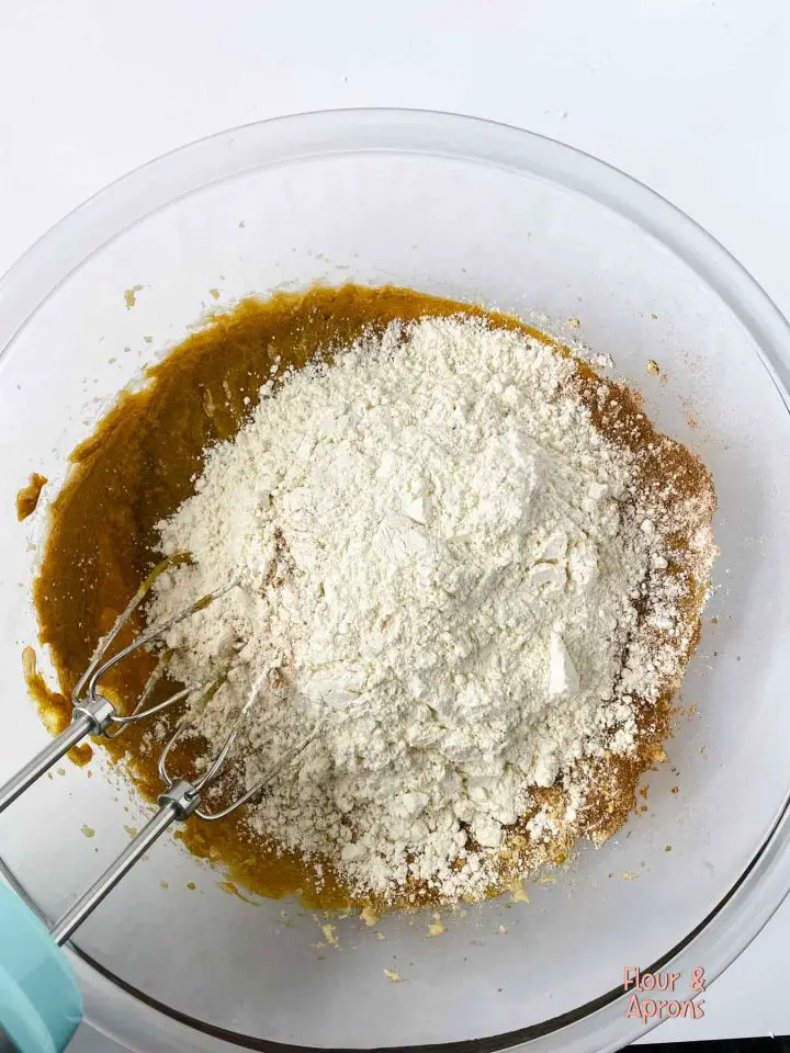 Flour mixture being added to dough in a bowl.
