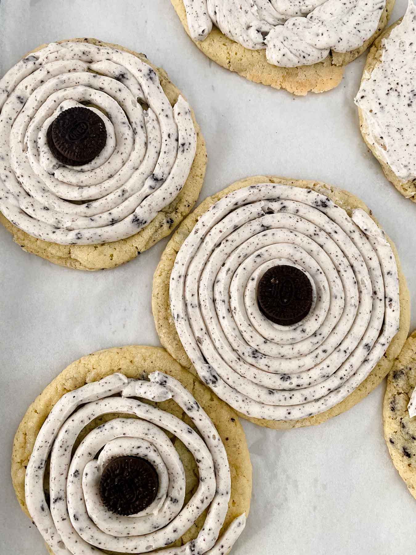 Top down view of baked and decorated Cookies and Cream cookies on parchment paper.