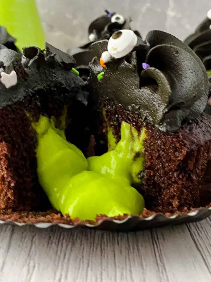 Closeup of cut in half green slime cupcake. 