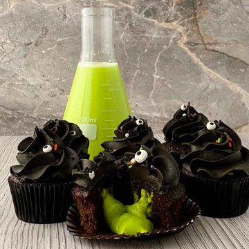 Slime cupcakes with the front one cut in half and oozing slime.