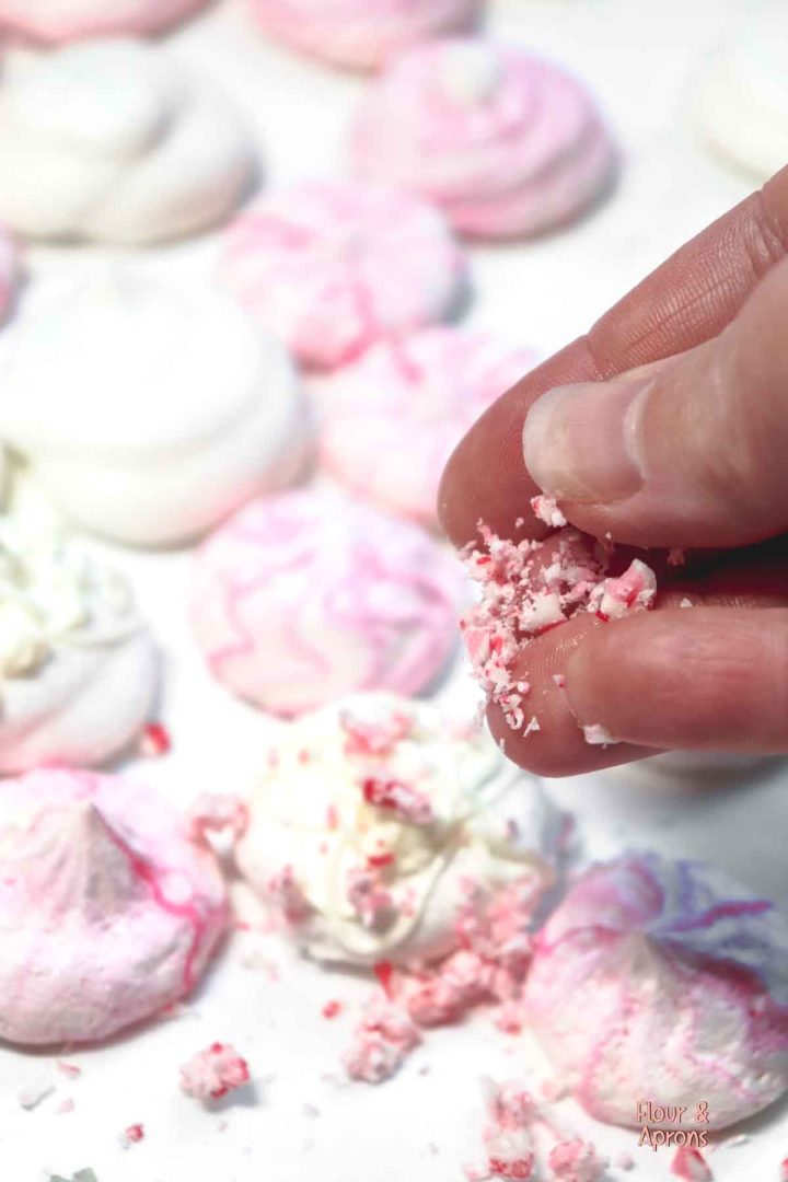 Sprinkling crushed candy cane onto meringues.